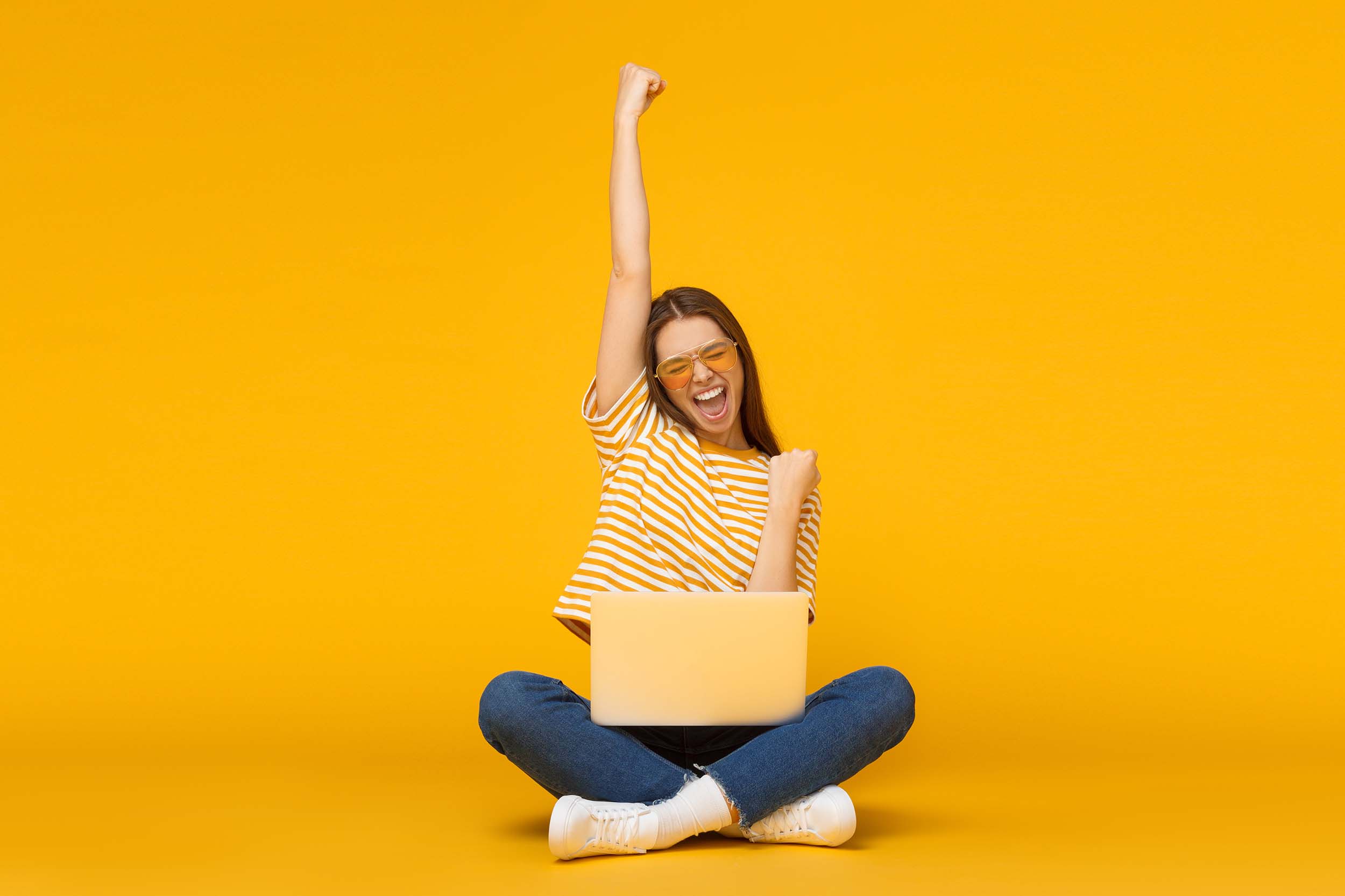 happy female with laptop isolated on yellow background